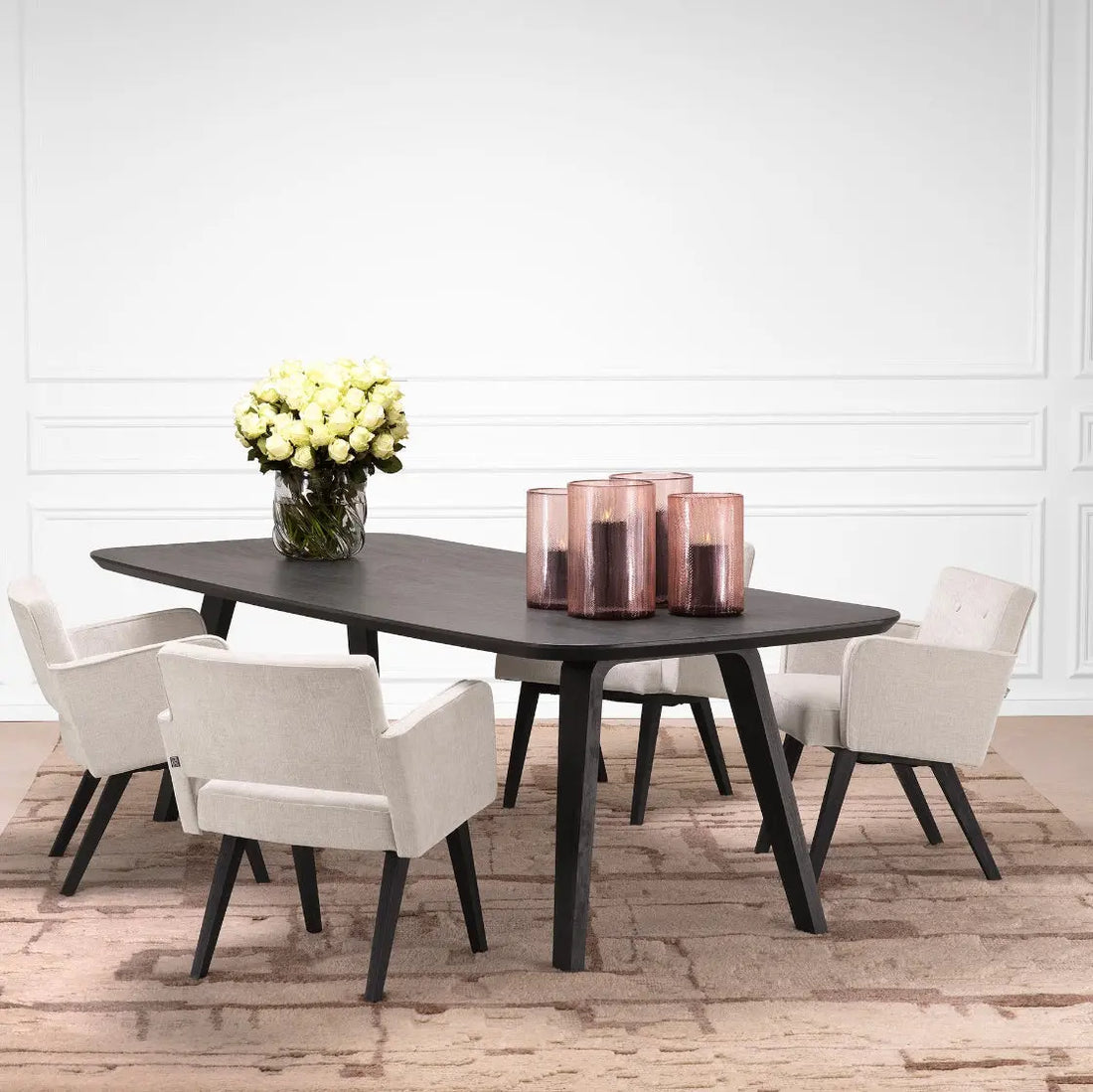 Dining table with chairs and decorative items in a room with white walls and wooden flooring.