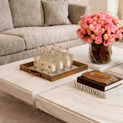 Decorative coffee table with candles, a vase of pink roses, and books in a living room setting.