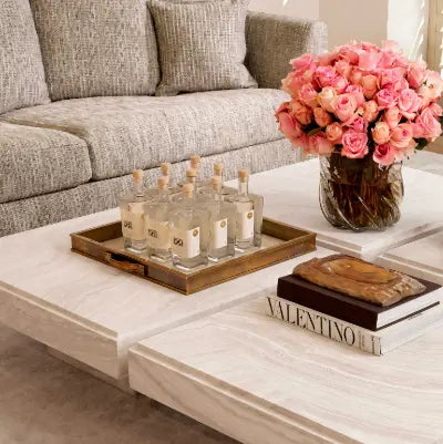 Decorative coffee table with candles, a vase of pink roses, and books in a living room setting.