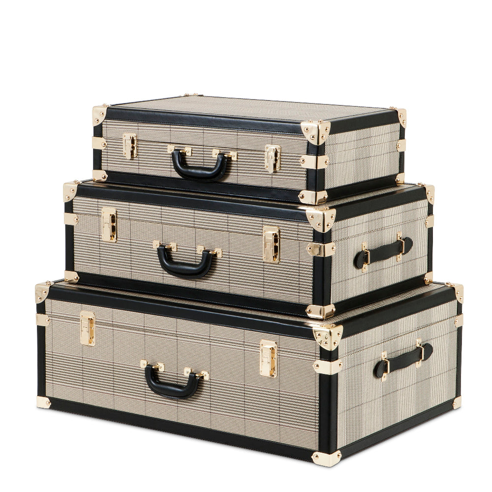 A set of three striped bittersweet trunks in black, beige, and gray, stacked on top of each other with gold decorative accents.