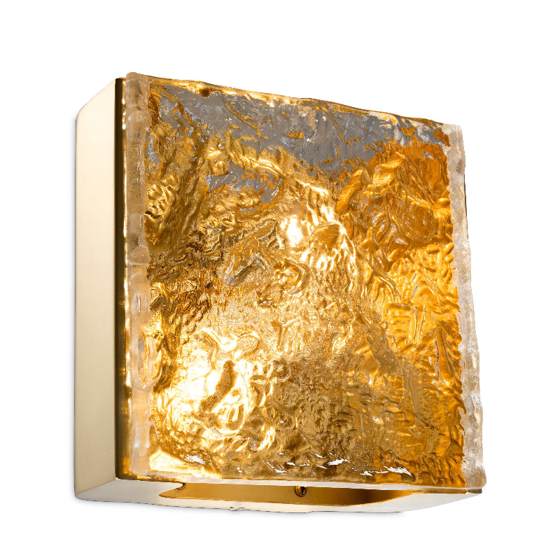 A square-shaped wall lamp with a gold-colored glass shade and a gold-colored base, providing a warm illumination.