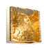 A square-shaped wall lamp with a gold-colored glass shade and a gold-colored base, providing a warm illumination.