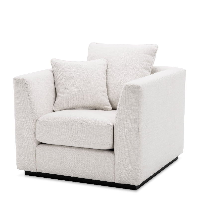 A modern armchair with a clean-lined silhouette, featuring a black metal frame and beige fabric upholstery with multiple cushions.