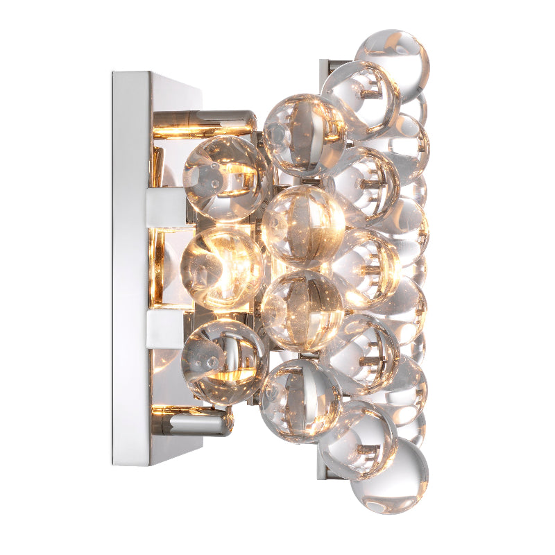 A wall-mounted lamp with a nickel finish and clear glass spheres that create a spectrum of colors by reflecting light.