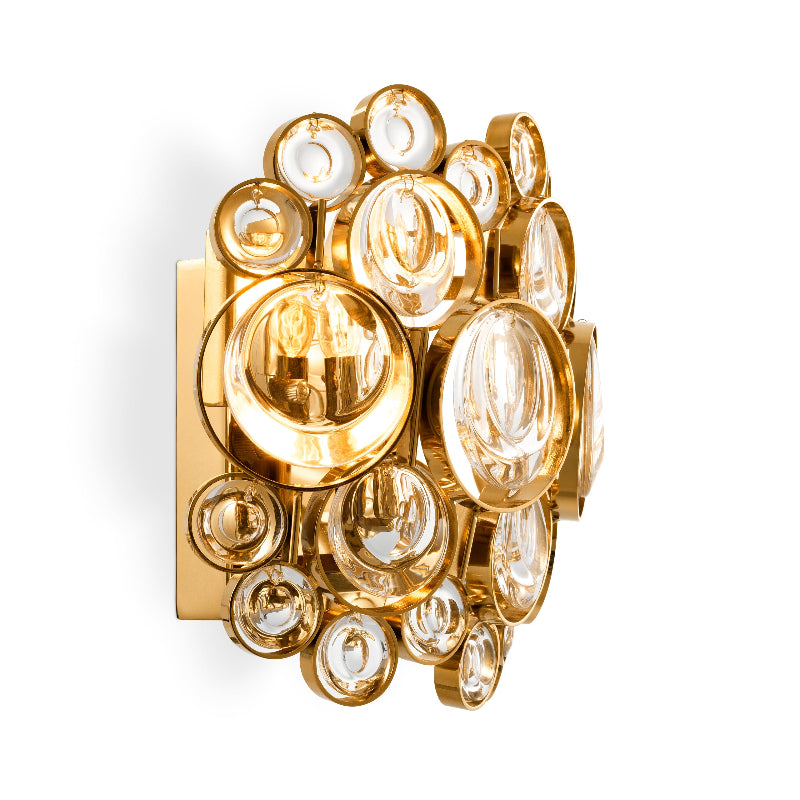 A semi-circular wall lamp with a gold-finished frame and clear glass pieces, reflecting light.