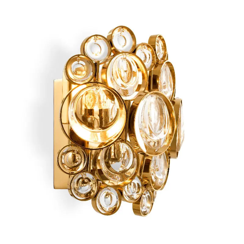 A semi-circular wall lamp with a gold-finished frame and clear glass pieces, reflecting light.