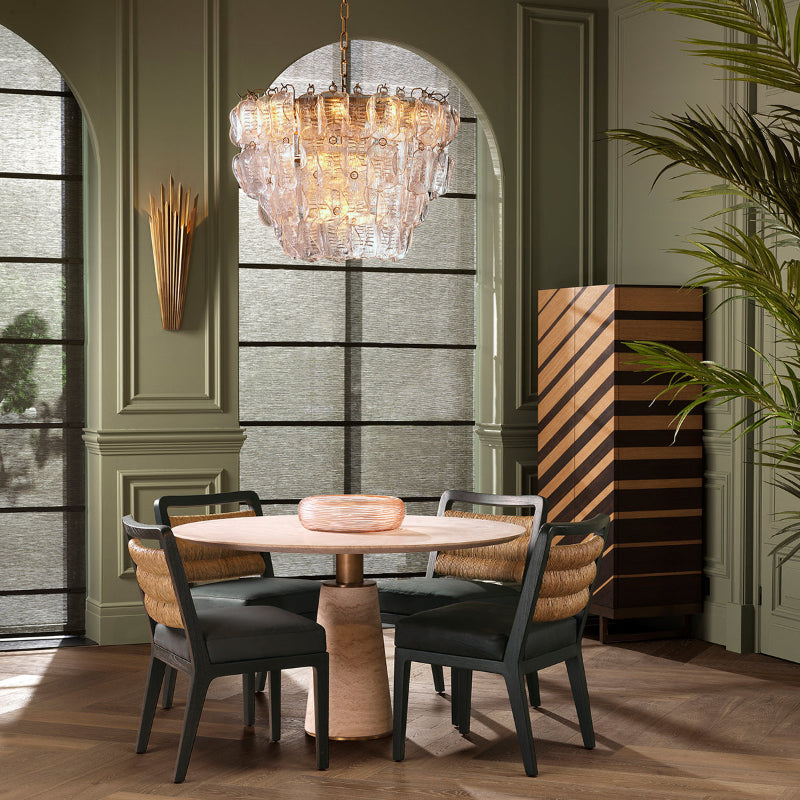 Dining room with round table and chairs, chandelier, and large window.